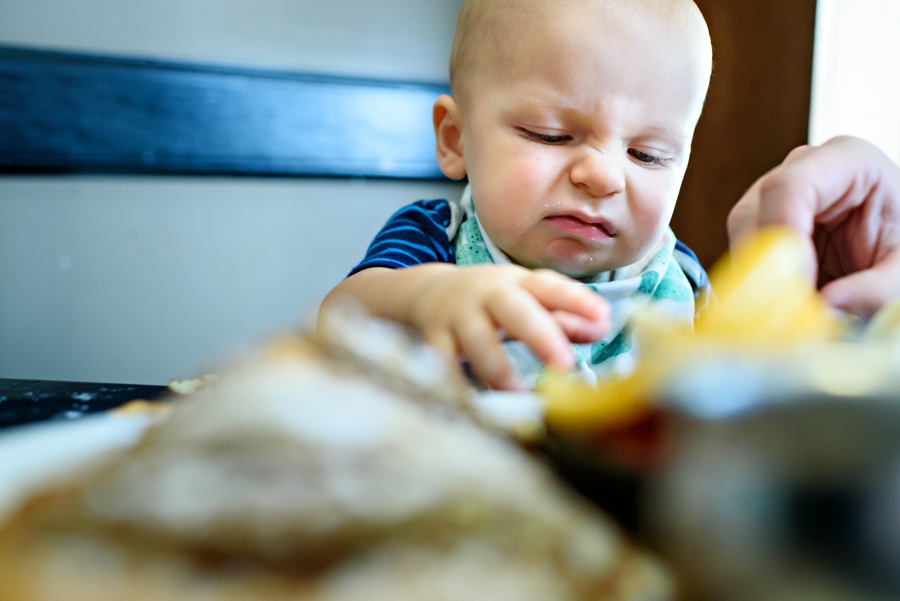 A baby making a funny face after eating a piece of fruit for the first time.